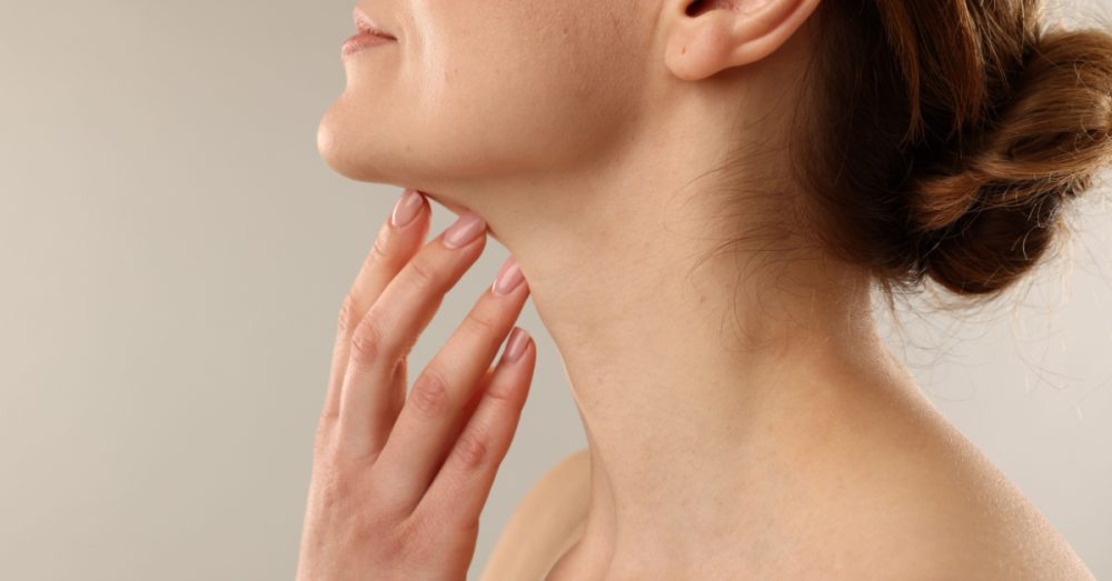 Woman touching her smooth, contoured neck and jawline